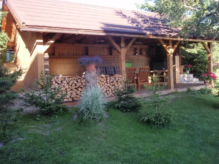 Krytá dřevěná pergola s posezením na zahradě
